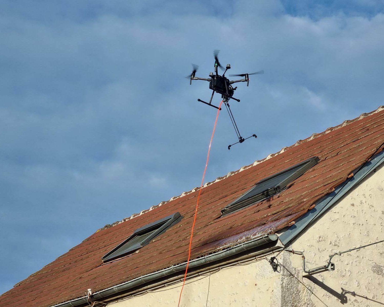 Drone BatiWash appliquant le traitement sur une toiture en tuiles